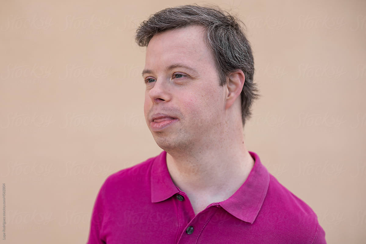 Portrait of young man with down syndrome on a yellow background