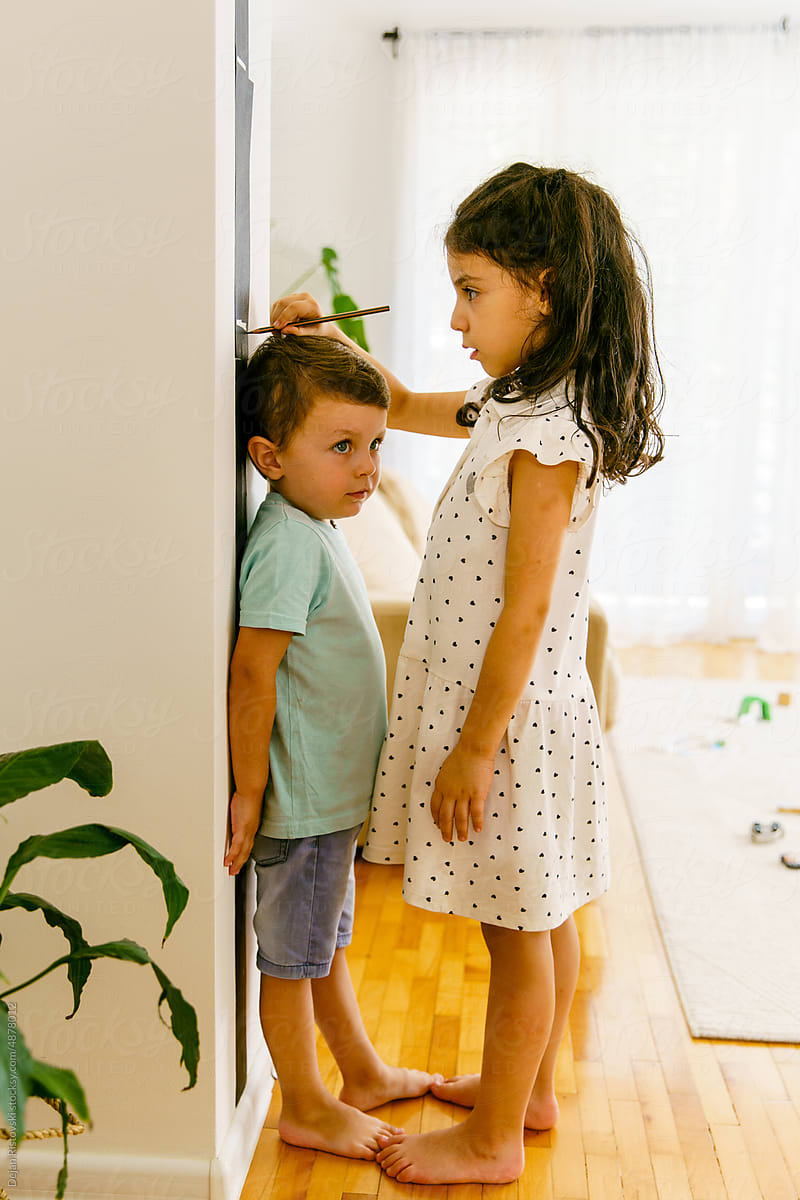 Girl measuring high of her little brother