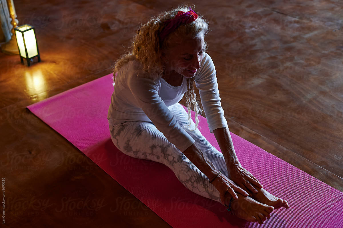 Smiling senior woman doing yoga on a mat