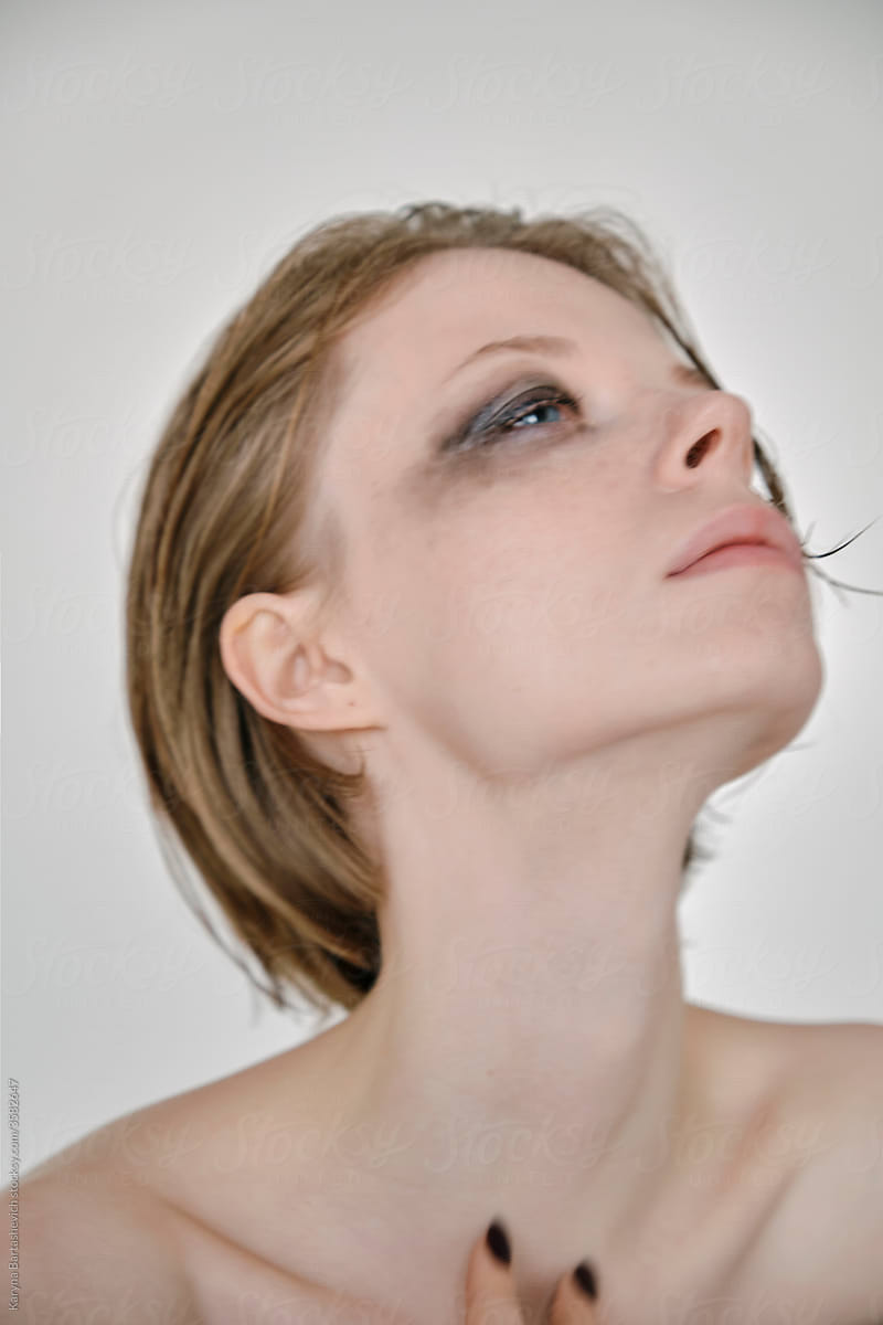 portrait of a fragile girl with a strong gaze, elegantly stretching her neck with bare shoulders