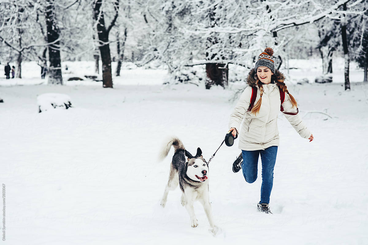 Young girl walking with husky in snowy park