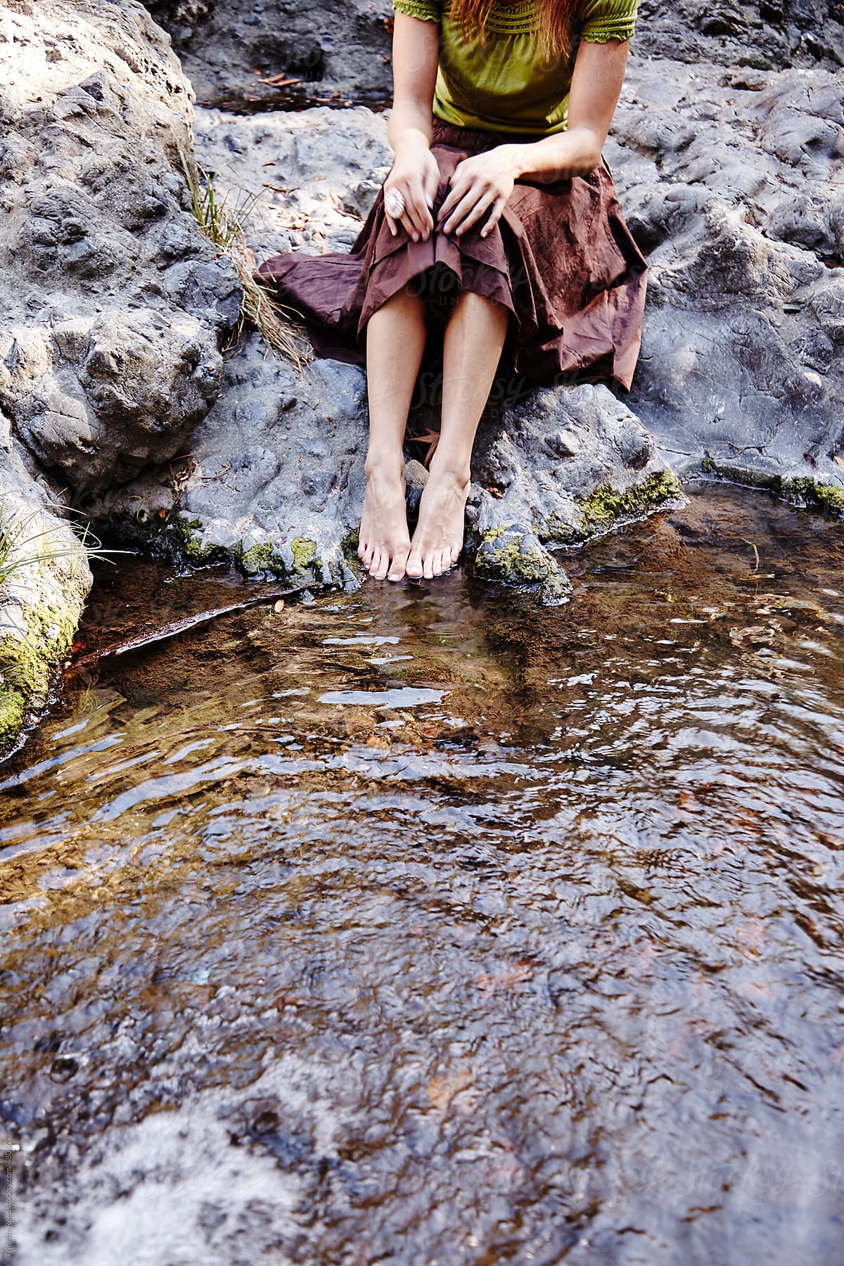 Woman relaxing in nature with feet in stream