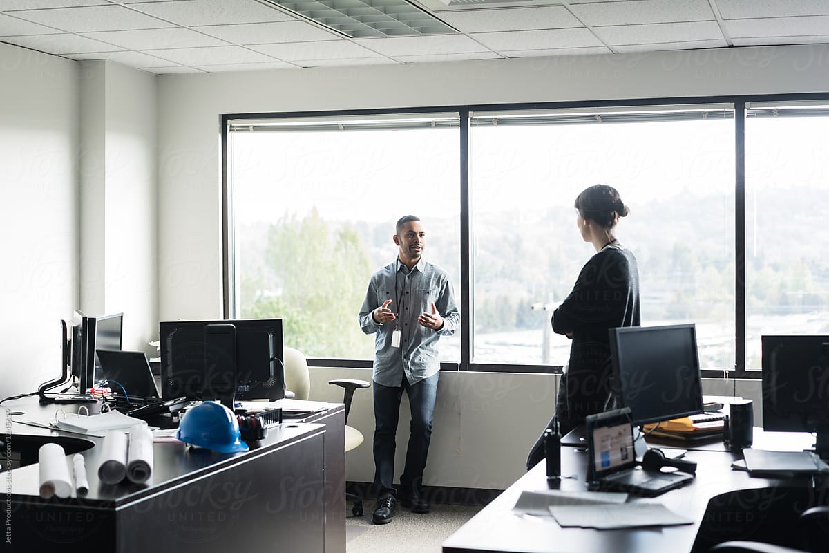 Two office workers talking in a brightly lit room