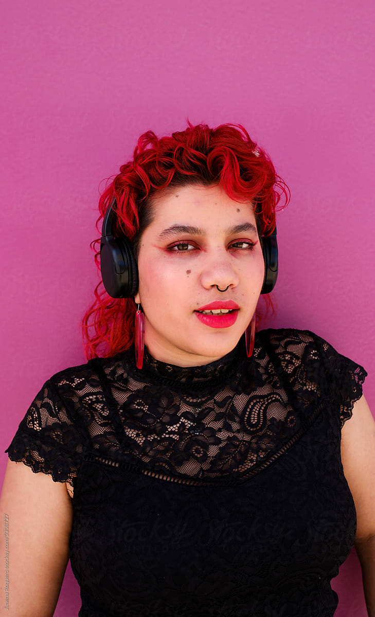 Portrait of Queer person over pink background looking at camera