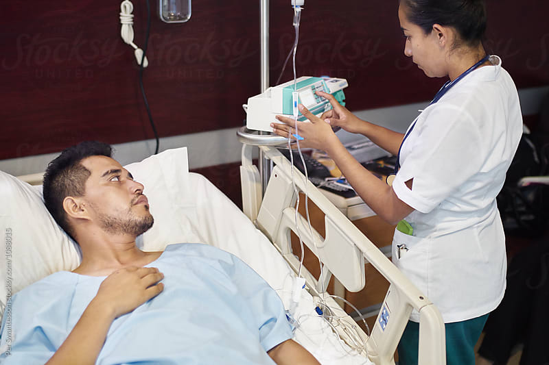Male patient looks at nurse setting IV pump machine