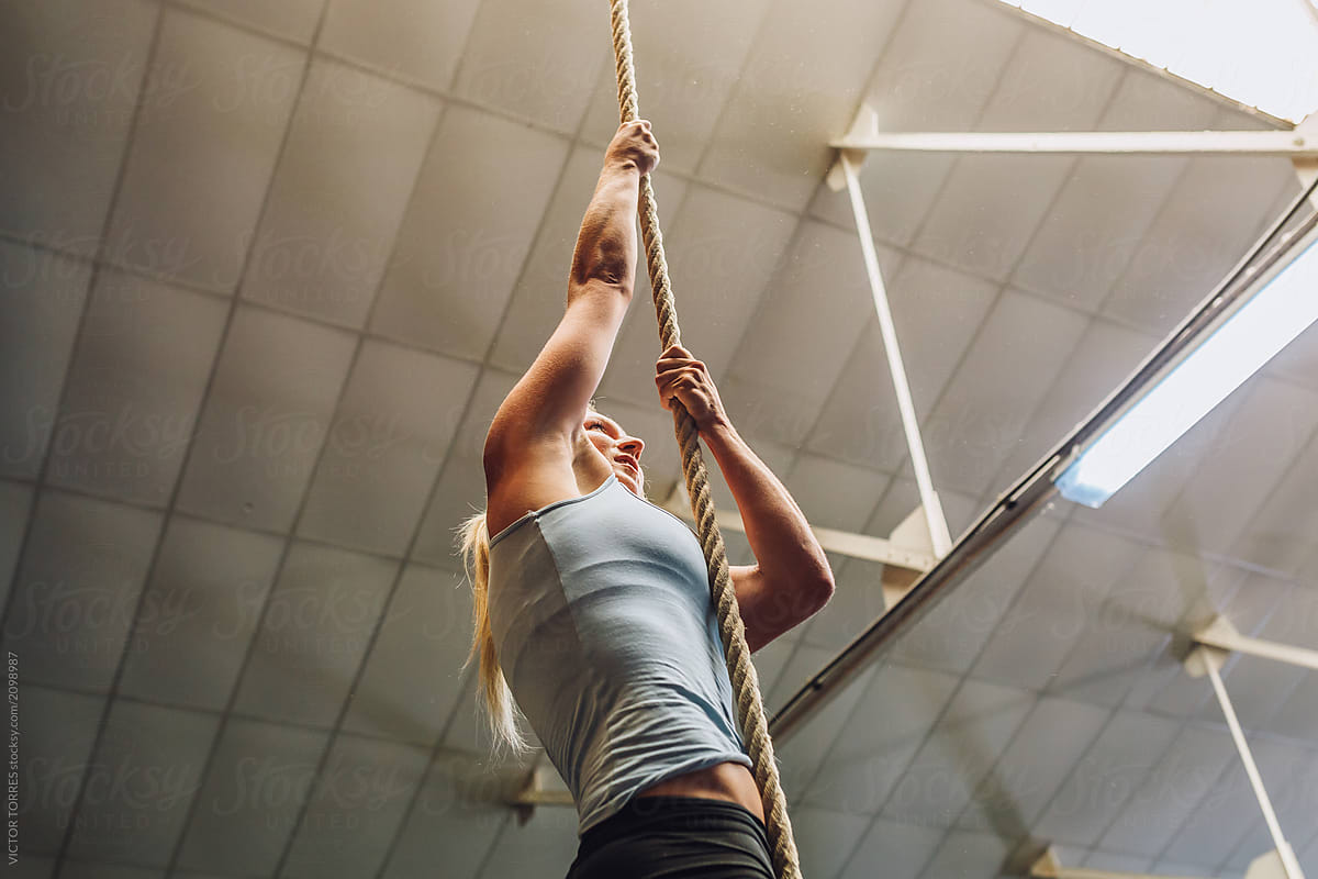 Strong woman climbing rope