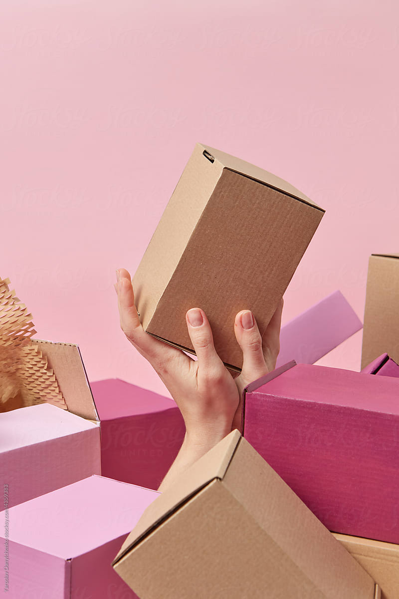 Female hand holding cardboard box among pile