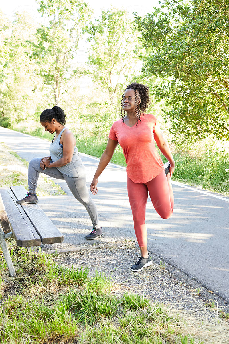 Mature Black women girlfriends stretching together in nature for a run