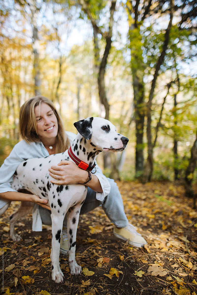 Young woman smiling at her dog while sitting next to it