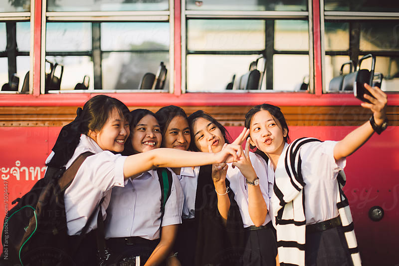 Thai school girl group making selfie together at the bus stop afterschool