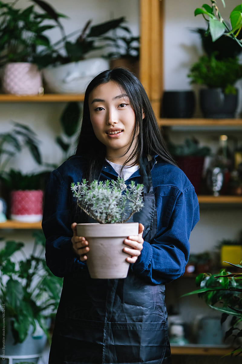 Smiled florist with potted herb in spacious  floral studio