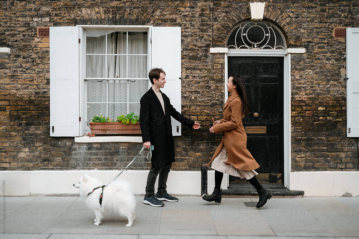 A man with a dog and a woman meet in front of a British house
