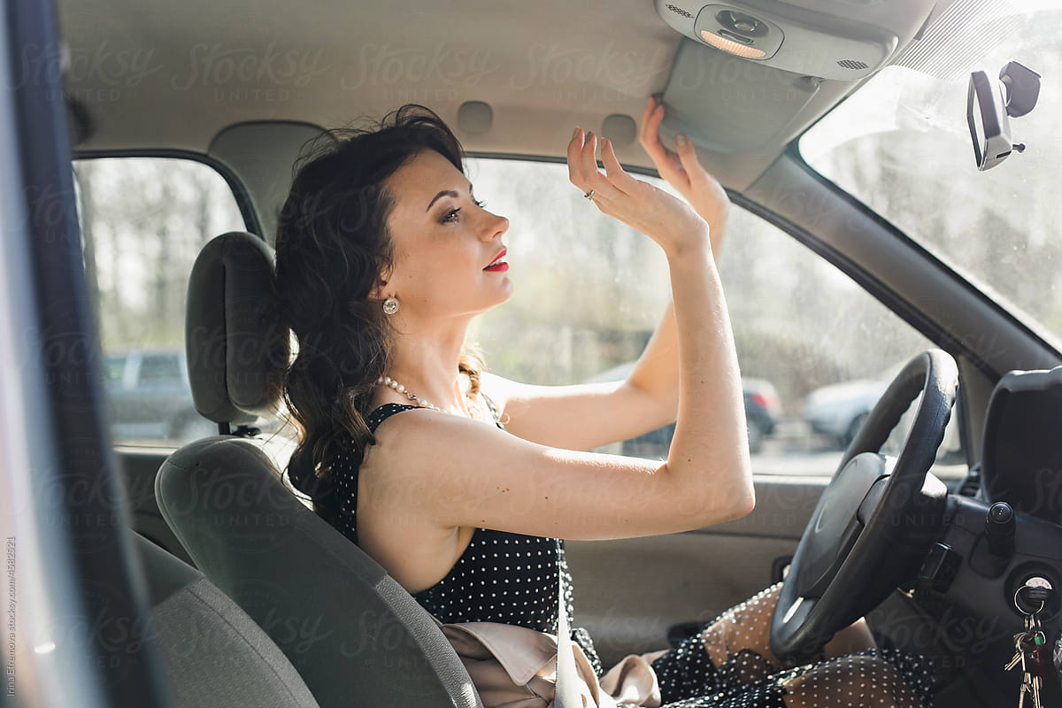 Woman adjusting a sun visor before starting a car