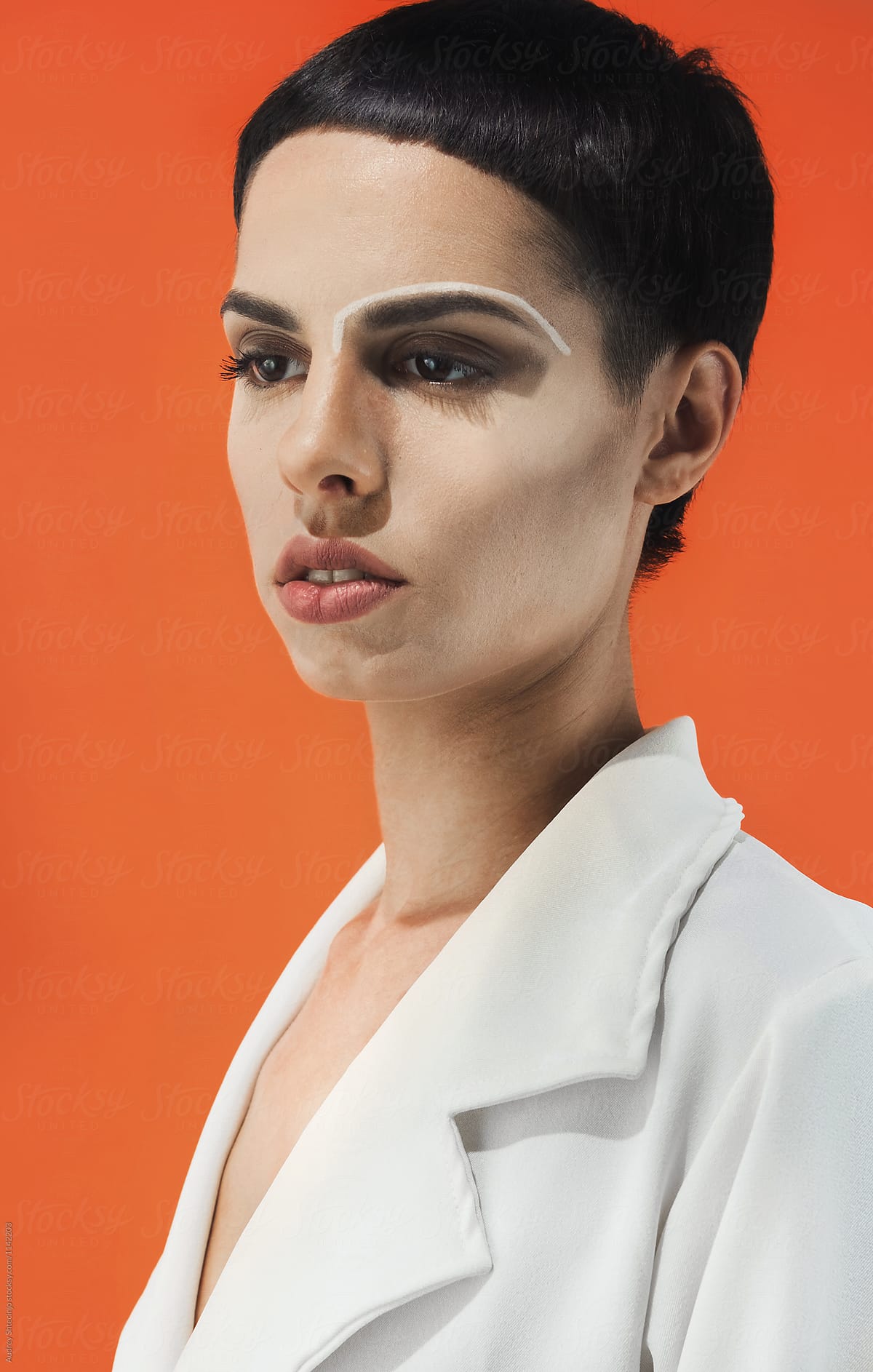 Fashion/conceptual portrait of female in white on orange background.