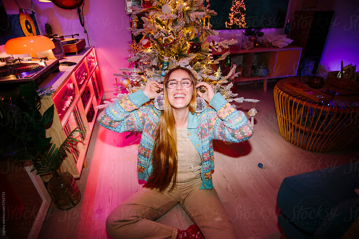 A woman laughing and playing around with Christmas ornaments