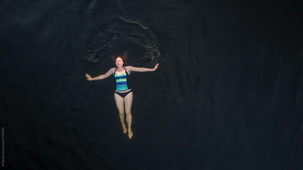Aerial Photo Of Woman Swimming Peacefully In Dark Freshwater Cottage Lake By Stocksy