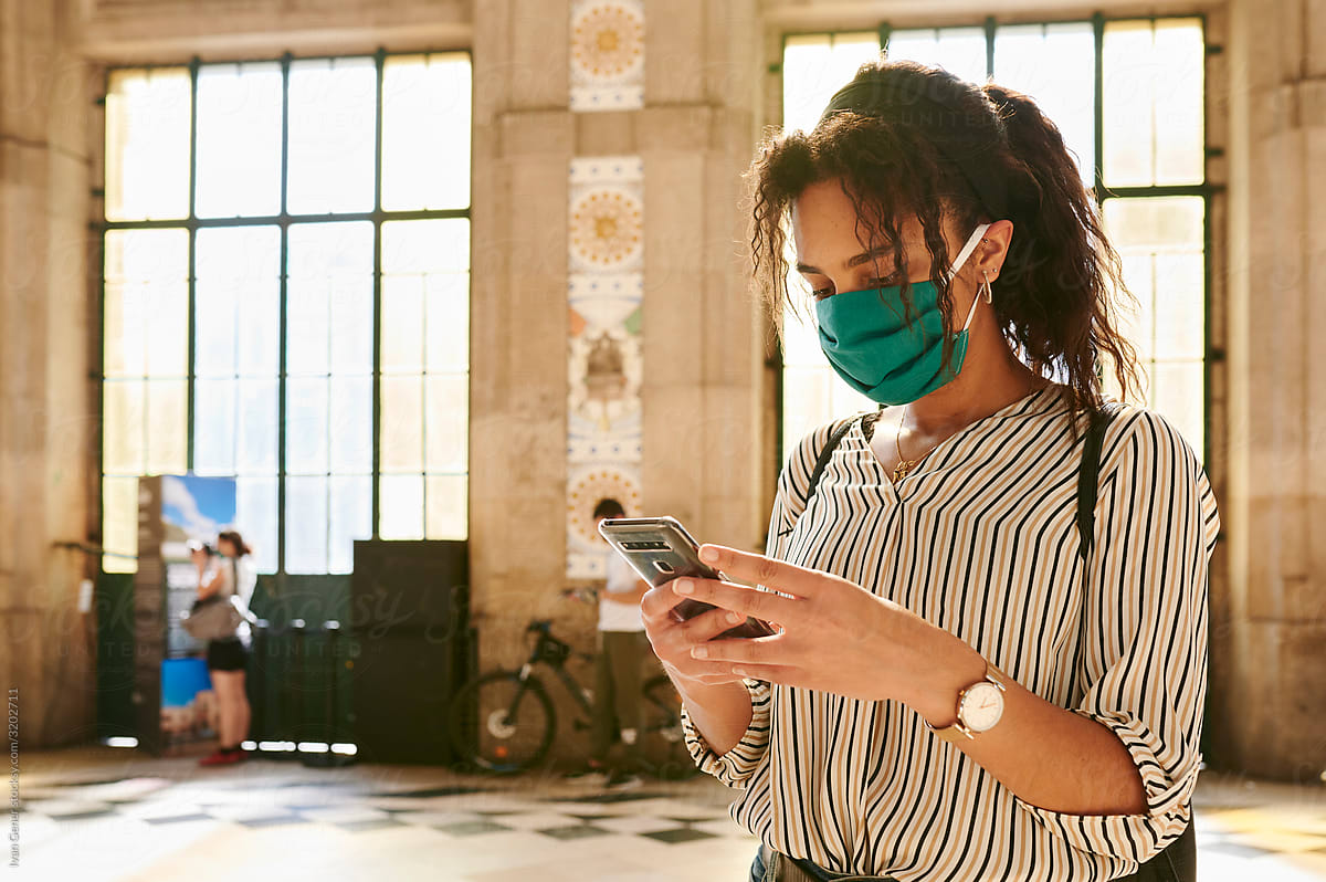 Woman wearing a face mask texting in a station