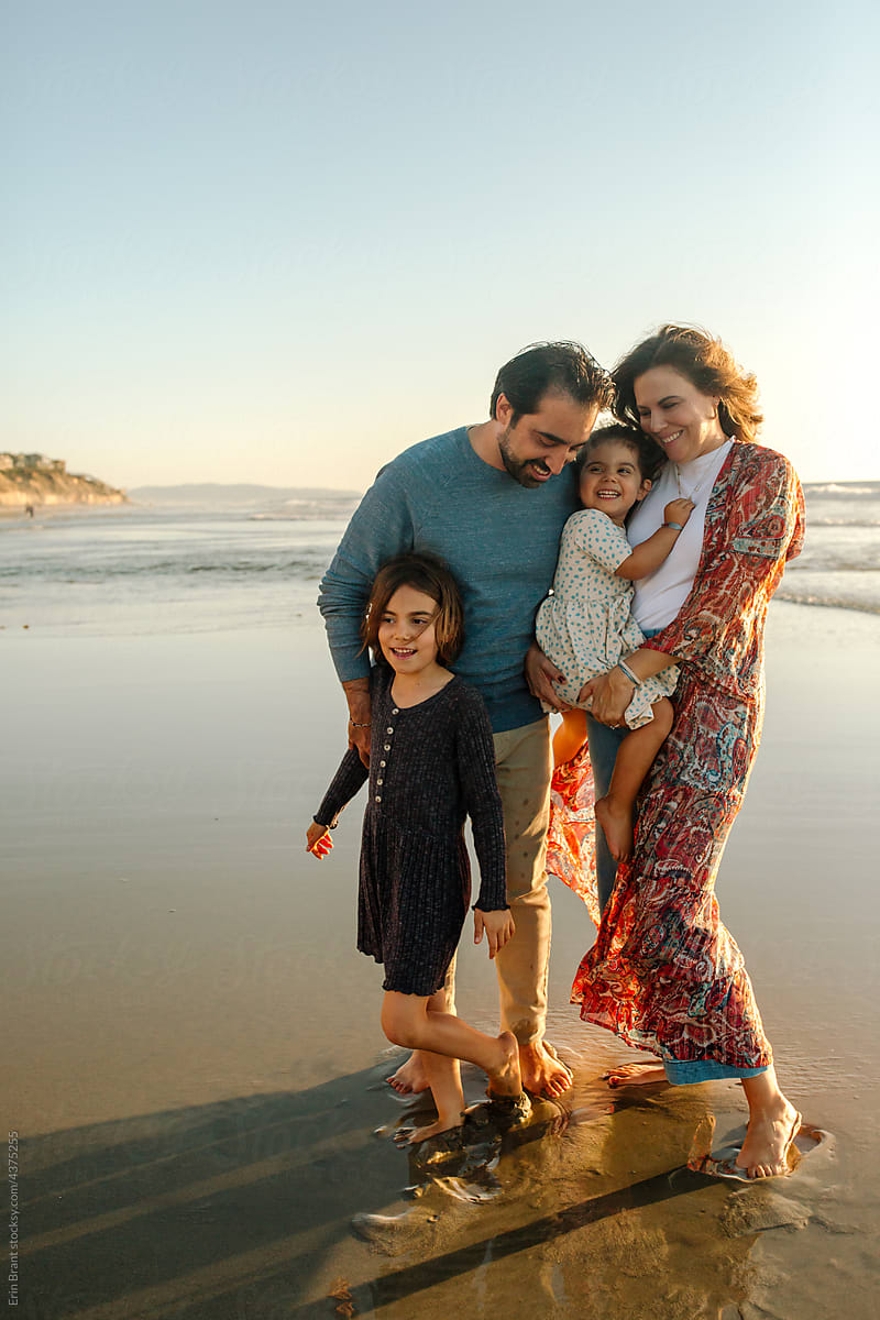 Beautiful family standing in ocean sand