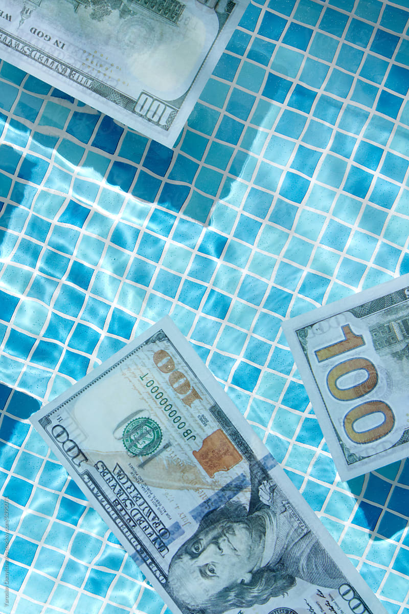100 dollar bills drifting in serene swimming pool water.