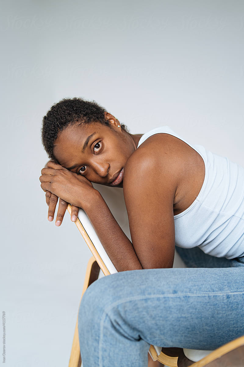 young melancholic black woman sitting on chair in studio