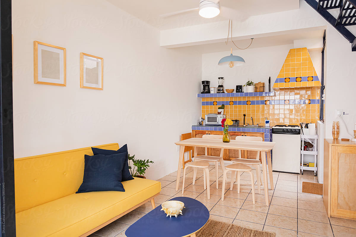 Yellow sofa with blue cushions next to a kitchen