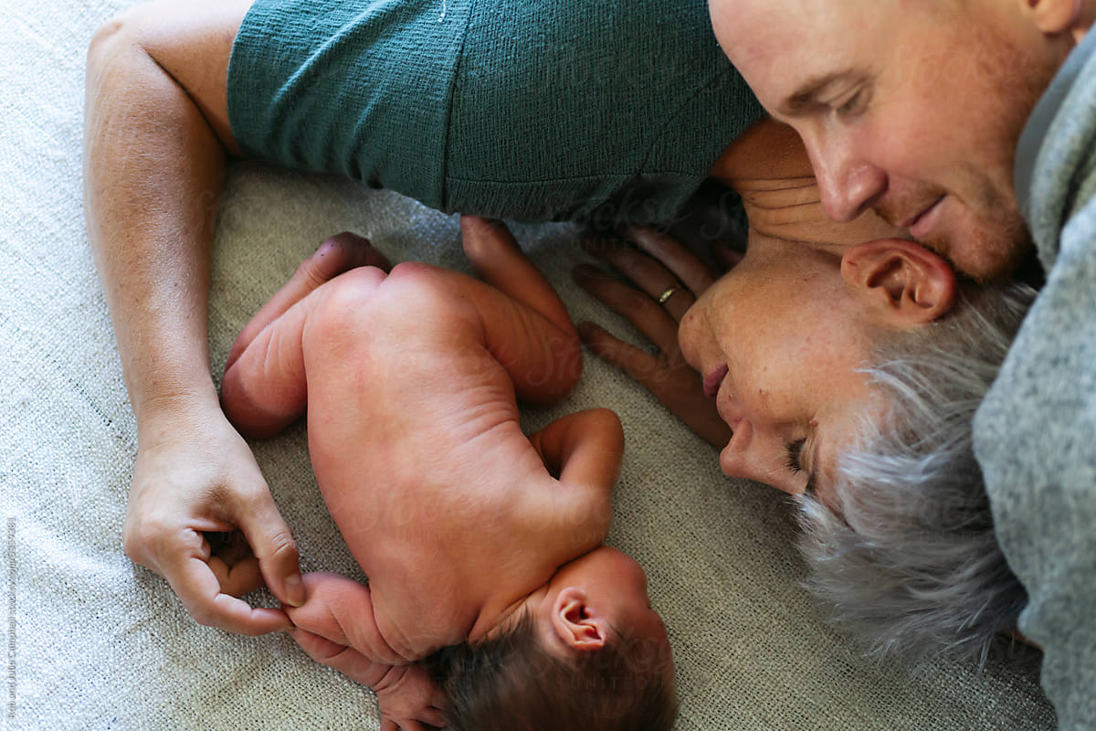 Man and Woman cuddling and staring happily at newborn.