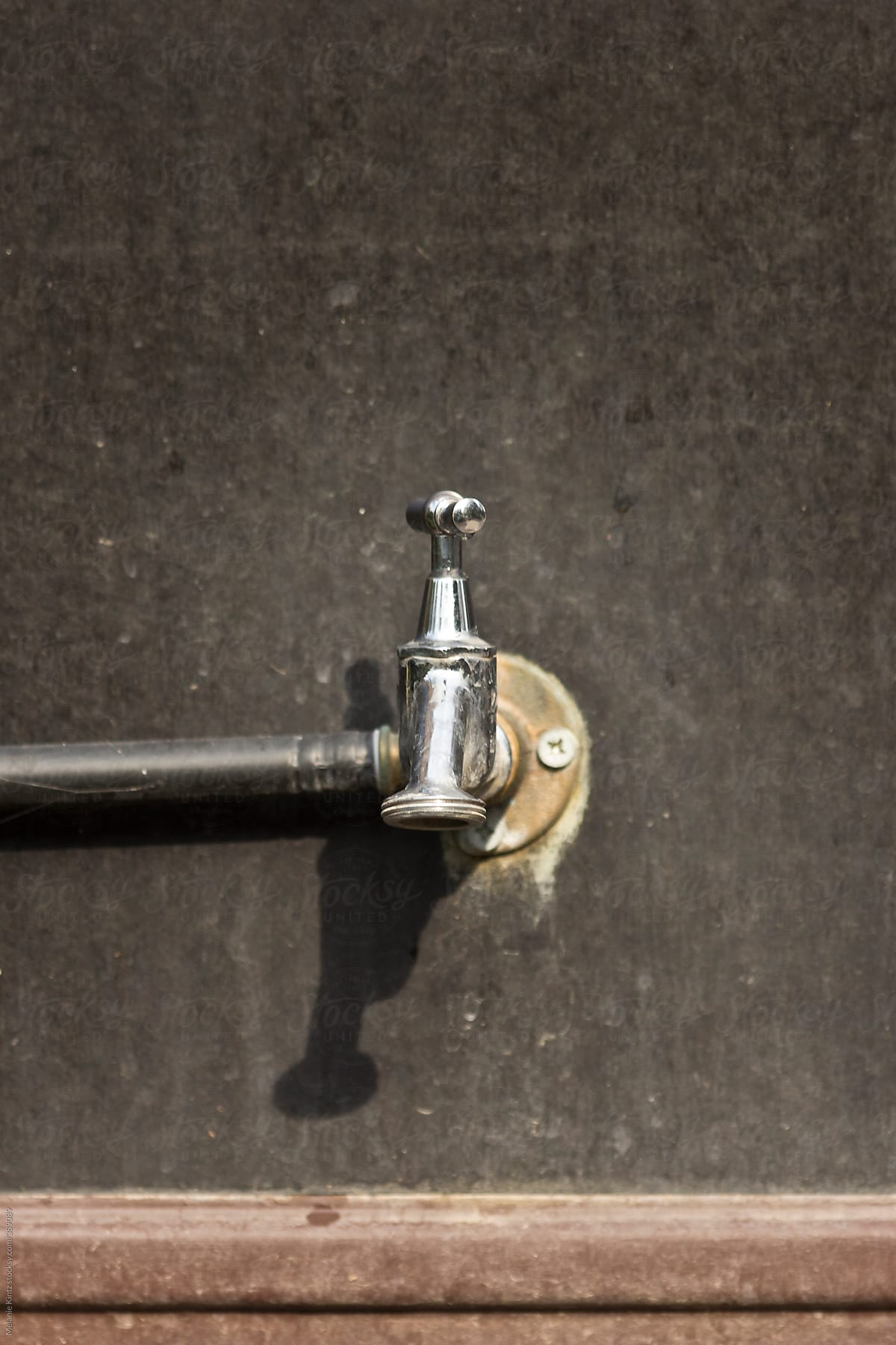 Outdoor water faucet on a dirty wall
