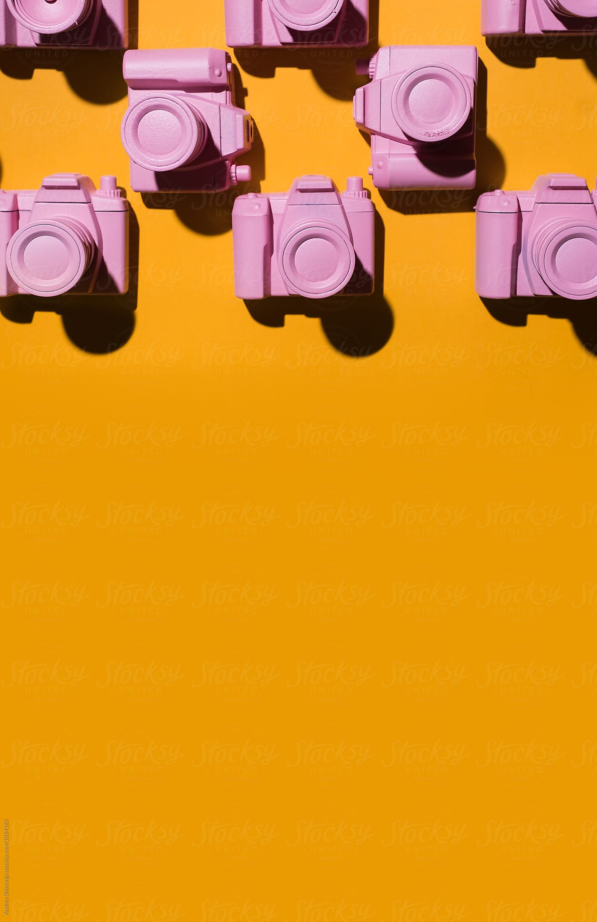 Pink cameras arranged on orange/yellow background.