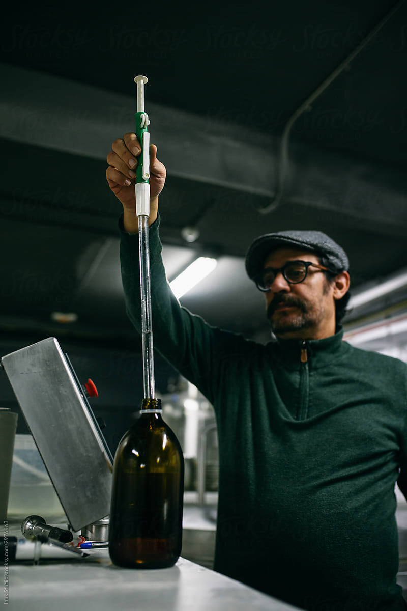 Adult brewer taking flavor extract from bottle