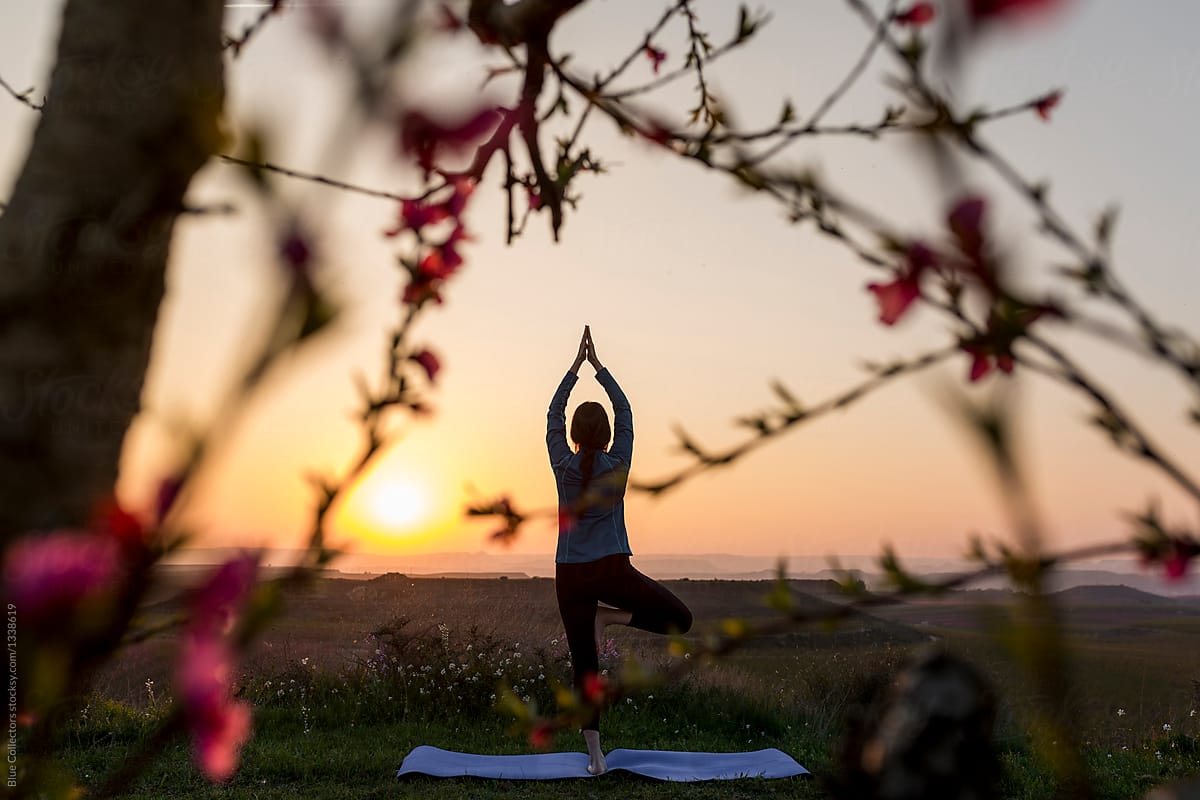 Woman practising yoga at sunset in the mountains, spring time