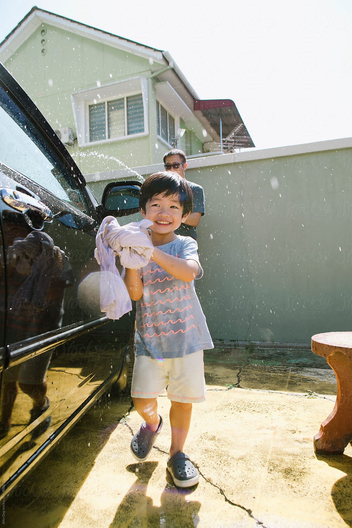 Little boy helping dad washing car