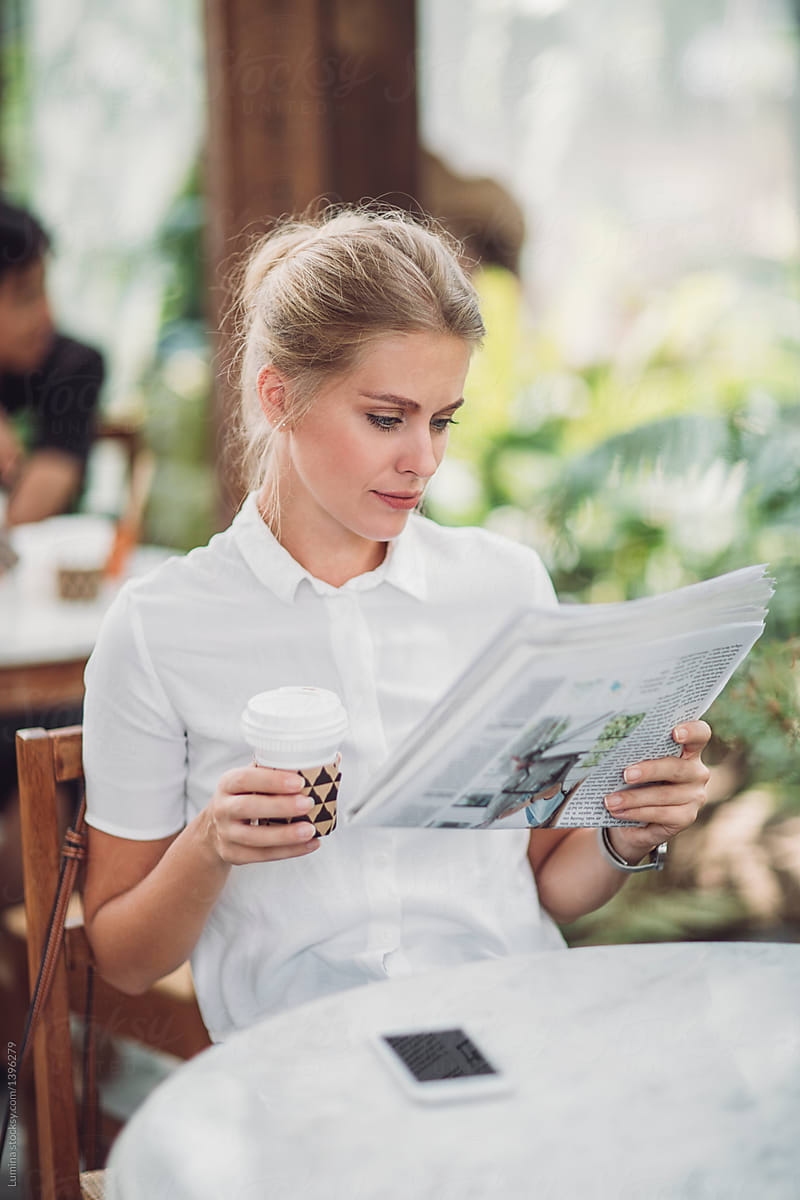 Woman Reading Newspapers at Coffee Shop