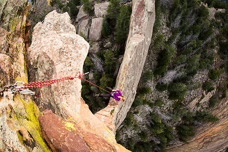 Young Adult Woman Rappels off exposed rock on the Maiden in Colorado
