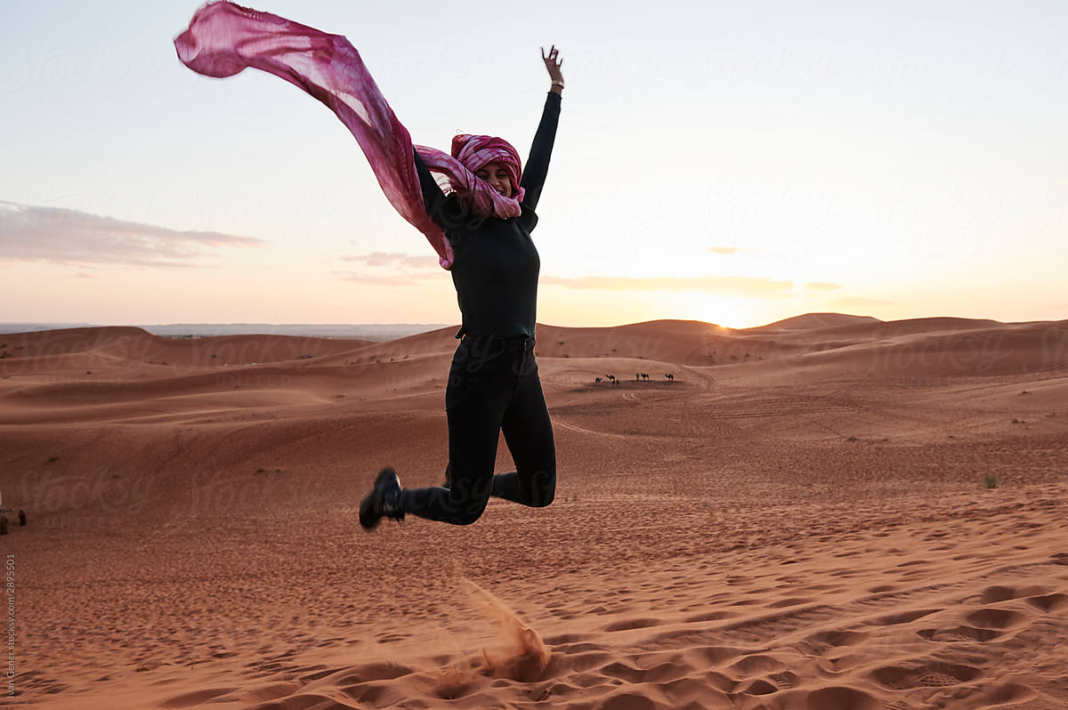 Happy woman turban jumping sunset desert