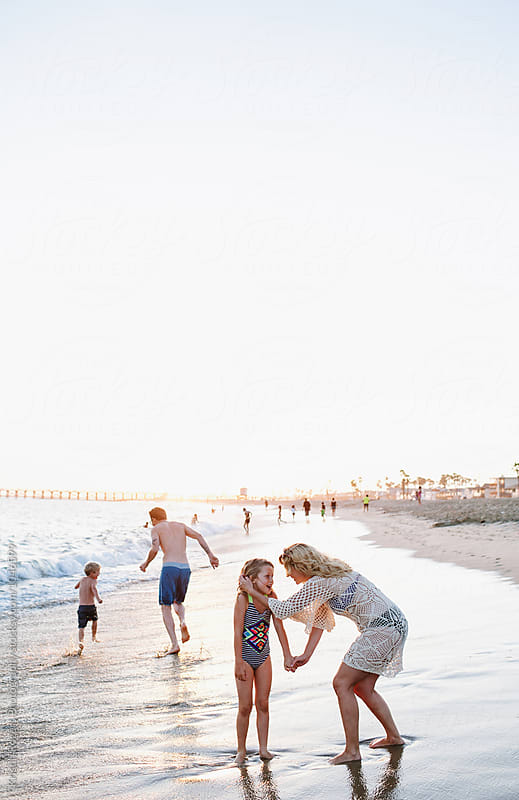 Family on beach at golden hour playing in water
