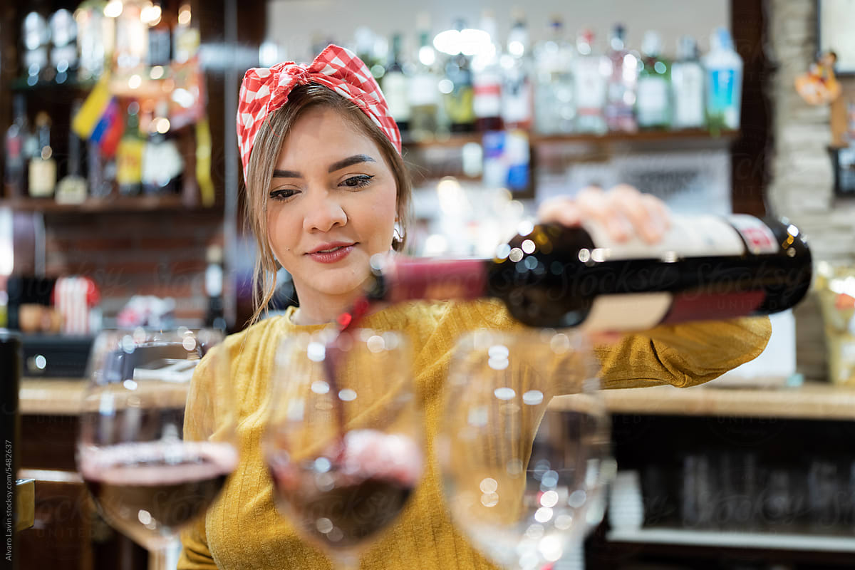 Waitress serving wine in glass.