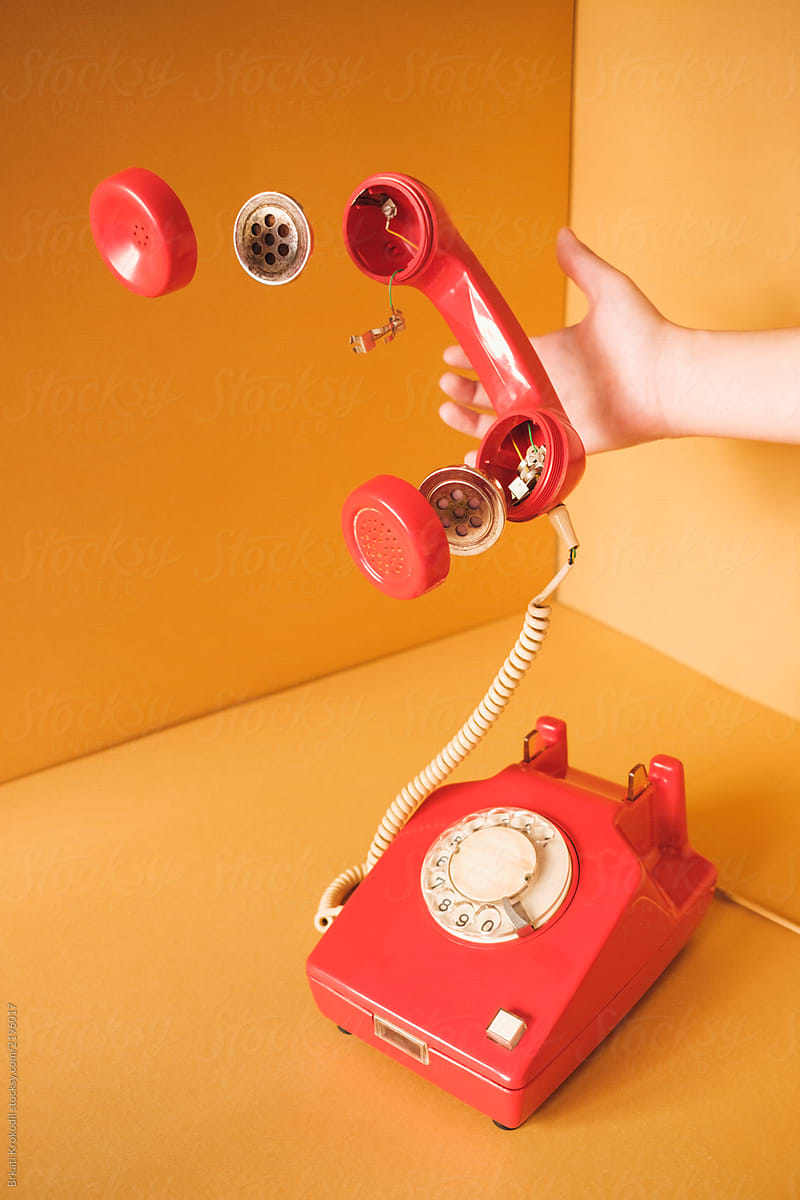 Hand Holding Retro Red Telephone With Parts Floating In The Air