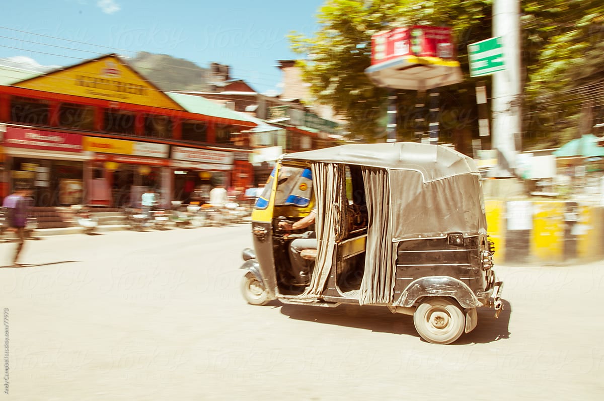 A motorised tuk-tuk travelling through an Indian village