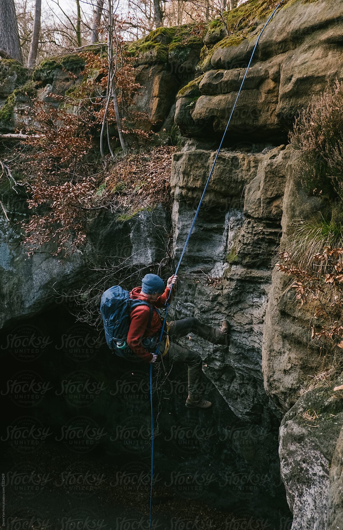 A man climbing down, a descent off a cliff.