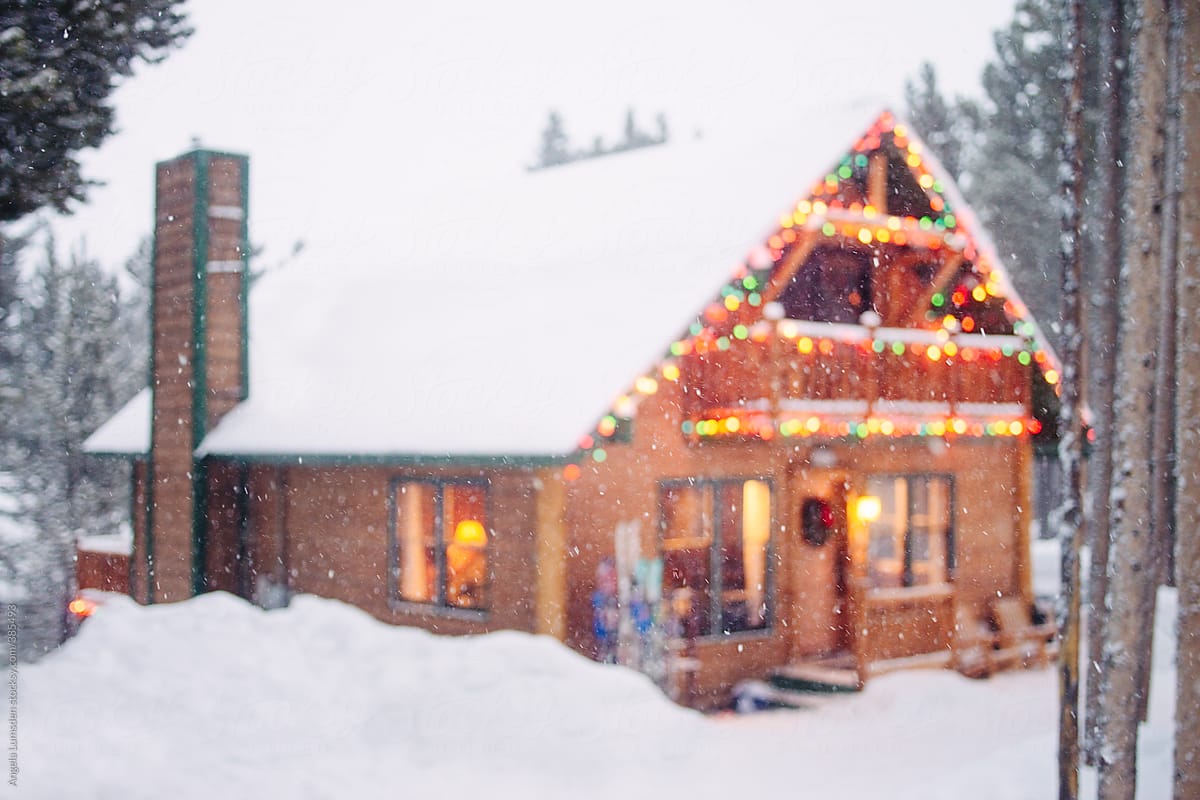 Cosy cabin lit with holiday lights in the snow