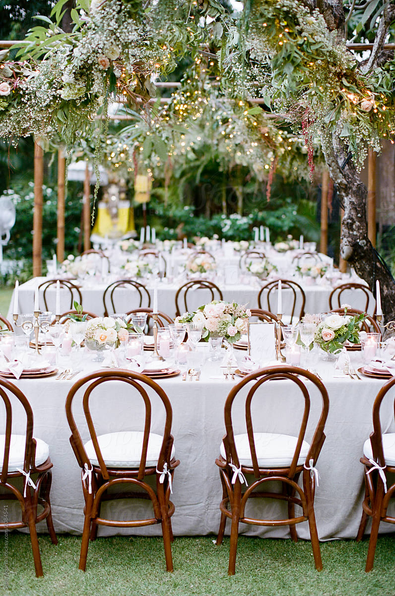 Outdoor, tropical wedding reception with hanging greenery garlands