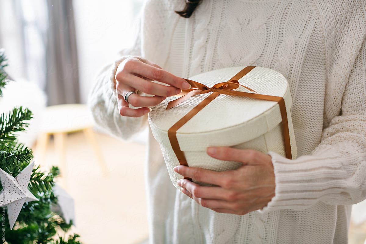 Closeup of a woman unwrapping a gift for Christmas time.