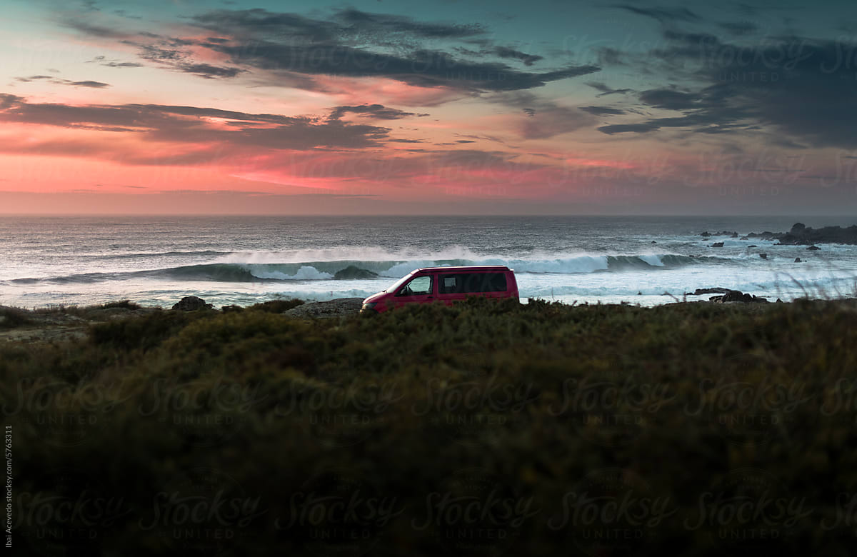 Camper van on wild coast with striking sunset sky