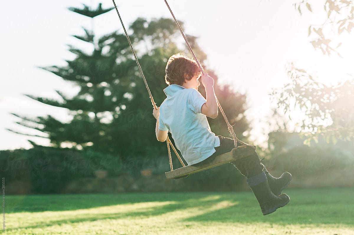 Child swinging on a large rustic tree swing