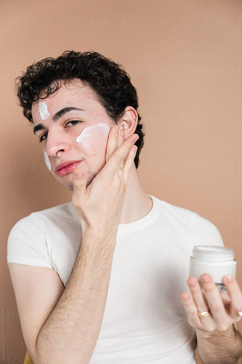 Young man applying facial cream