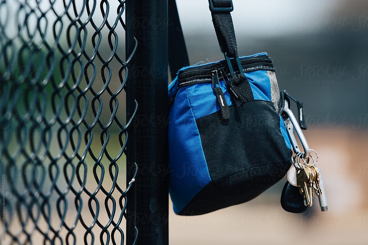 Lunch box with key chain hung on a fence at a baseball game