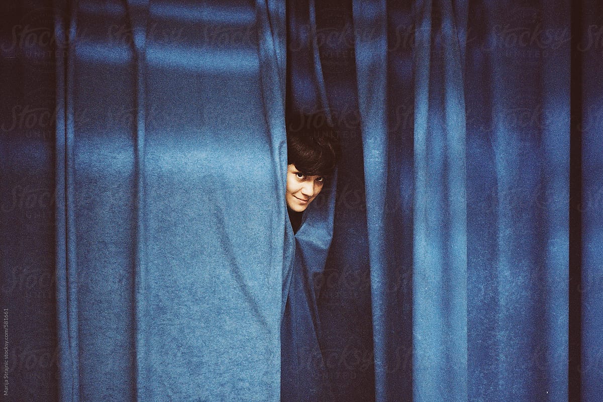 girl behind a blue theatre curtain