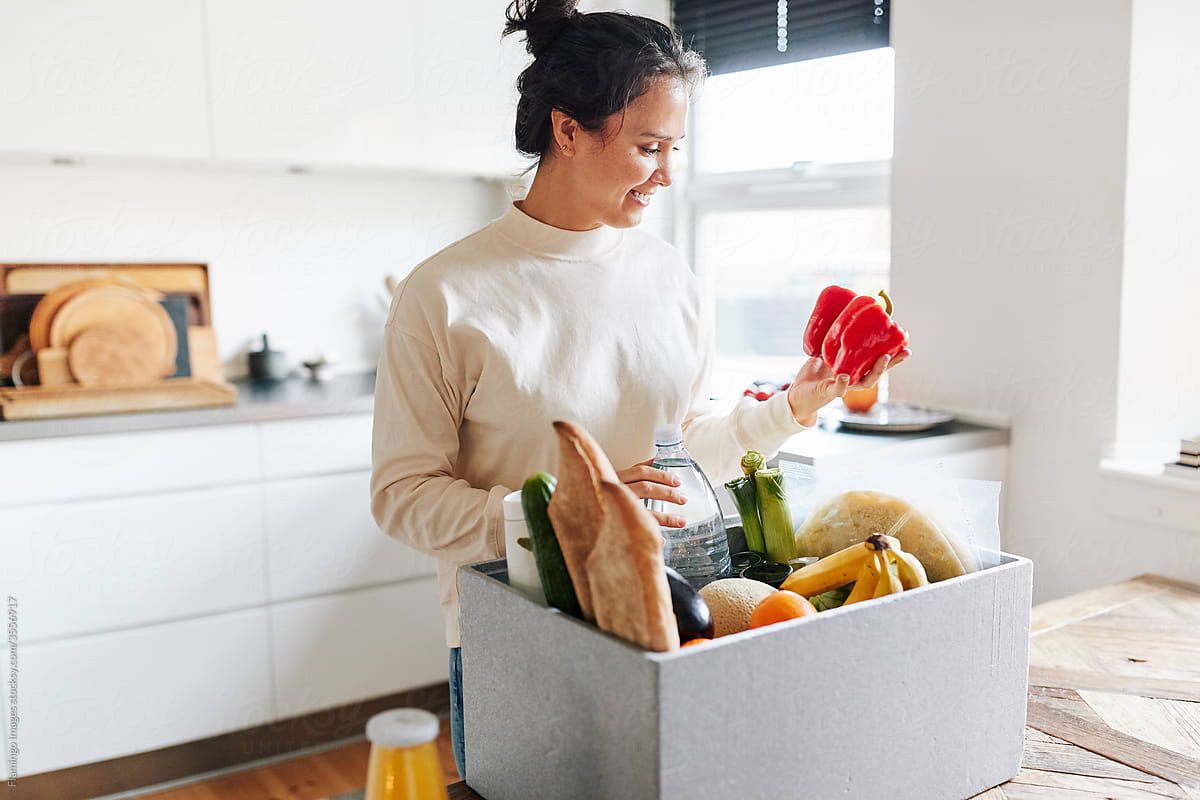 Smiling woman unpacking a box of fresh groceries