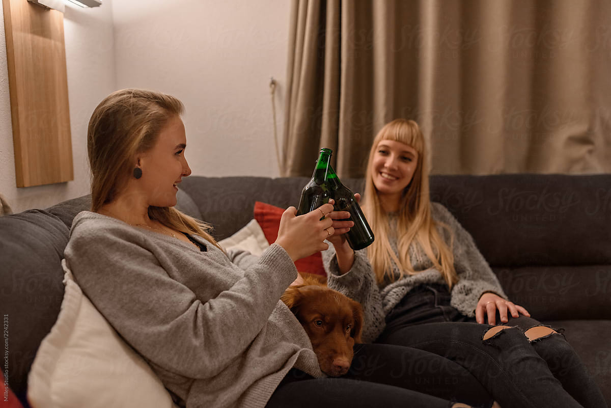 Women with dog on sofa having beer