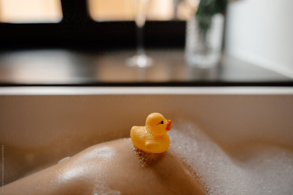 Anonymous woman taking bath with rubber yellow duck